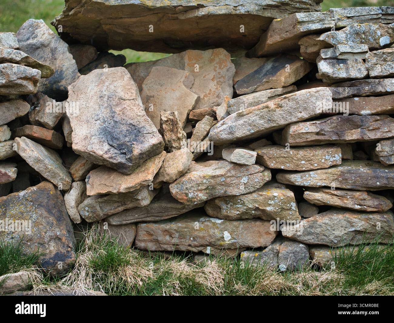 Pietre impilate di un rustico muro di pietra a secco vicino - Un dettagliato primo piano di un tradizionale muro di pietra a secco, che mostra la consistenza, i colori e la pacca naturale Foto Stock