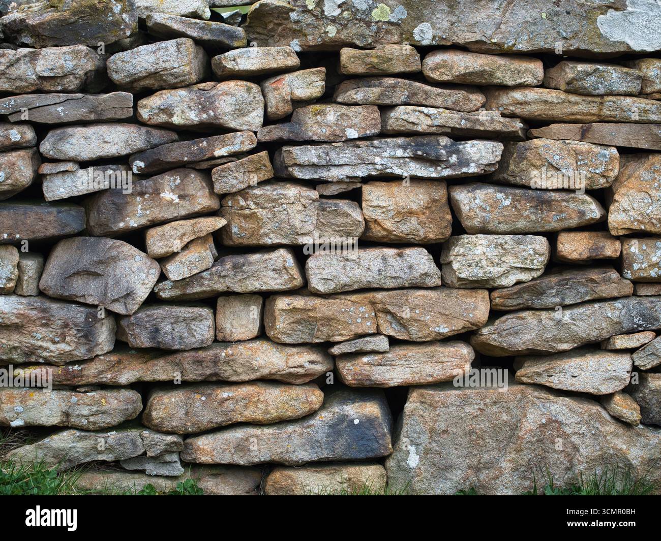 Pietre impilate di un rustico muro di pietra a secco vicino - Un dettagliato primo piano di un tradizionale muro di pietra a secco, che mostra la consistenza, i colori e la pacca naturale Foto Stock