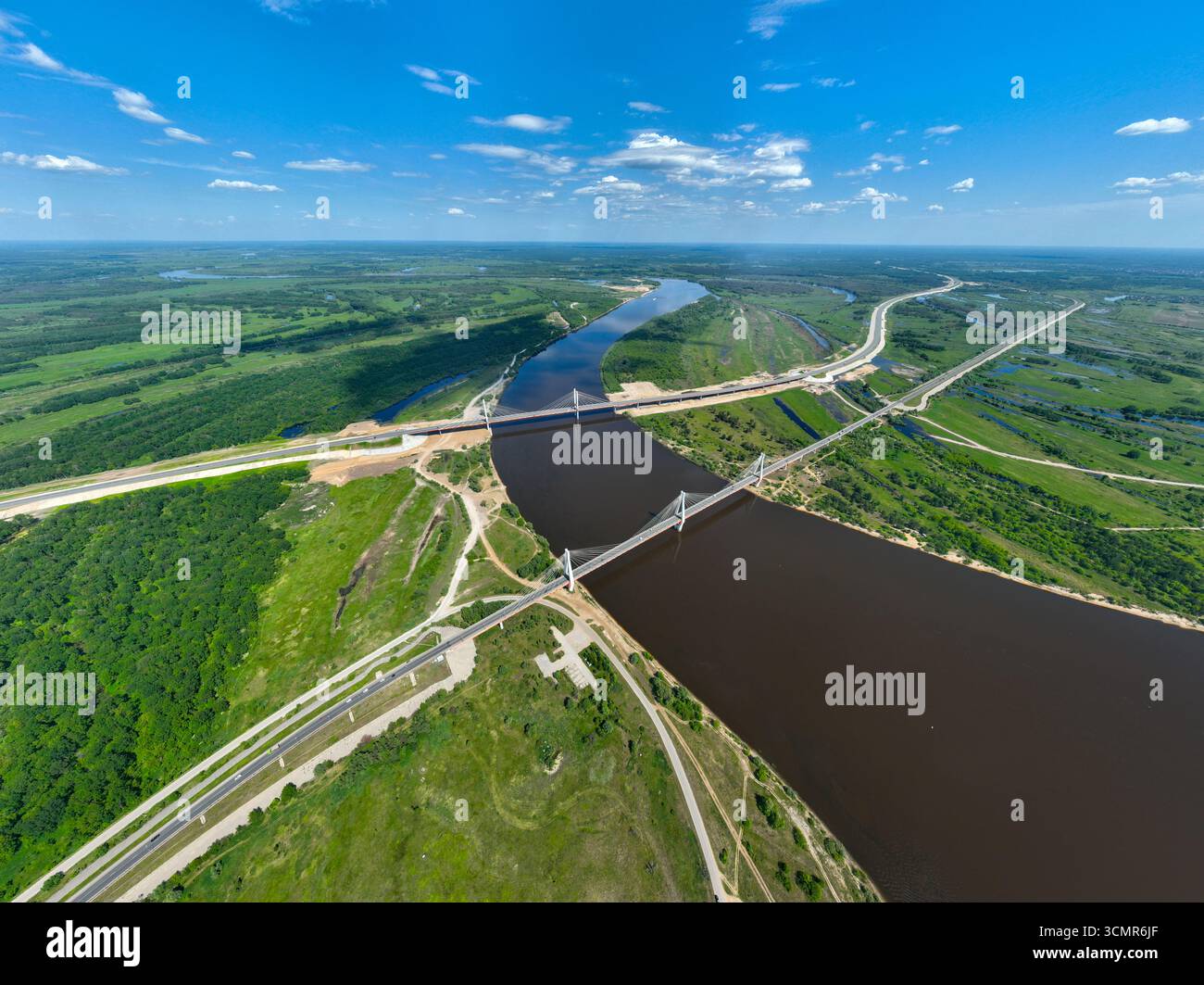 Ampia vista aerea del fiume Oka che si snoda attraverso un lussureggiante paesaggio verde con il ponte Murom e le autostrade circostanti visibili dall'alto. Foto Stock