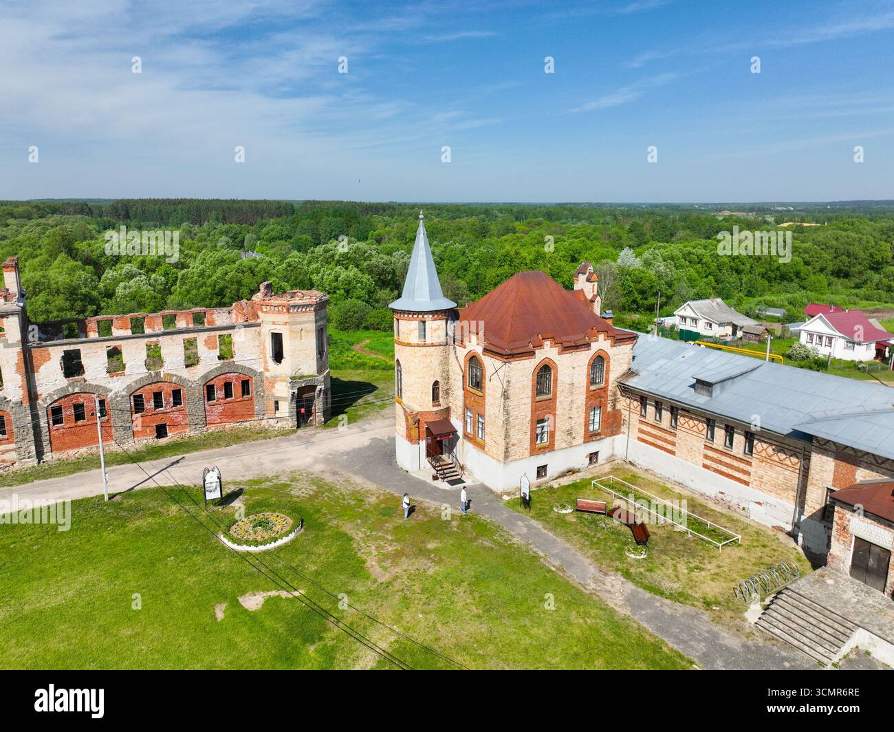 Una vista aerea delle parti parzialmente restaurate e rovinate del Castello di Khrapovitsky a Muromtsevo, con una lussureggiante foresta verde sullo sfondo. Foto Stock