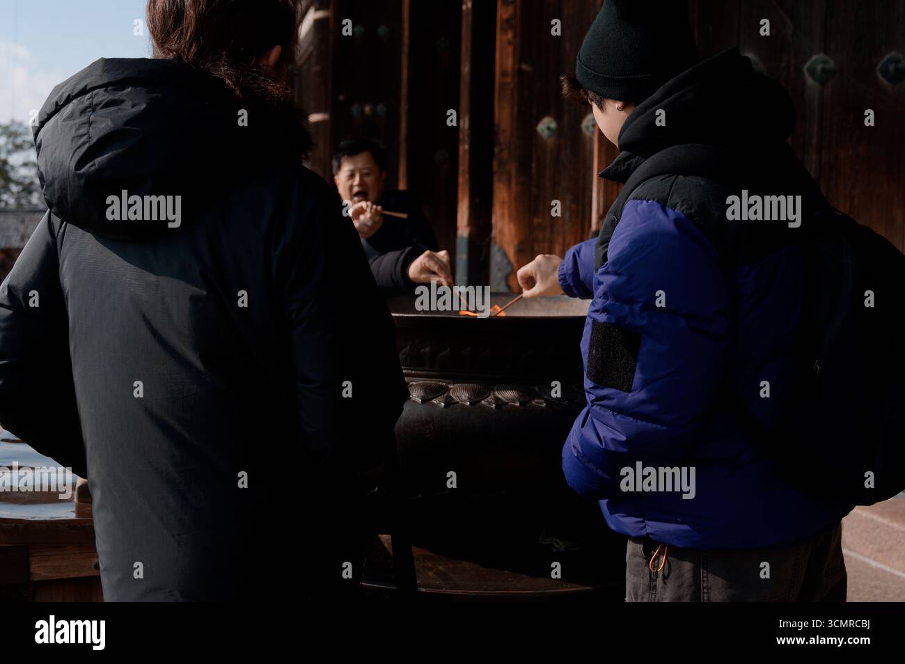 Le persone che illuminano i bastoncini di incenso in un grande bruciatore fuori dal tempio Todai-ji in inverno Foto Stock