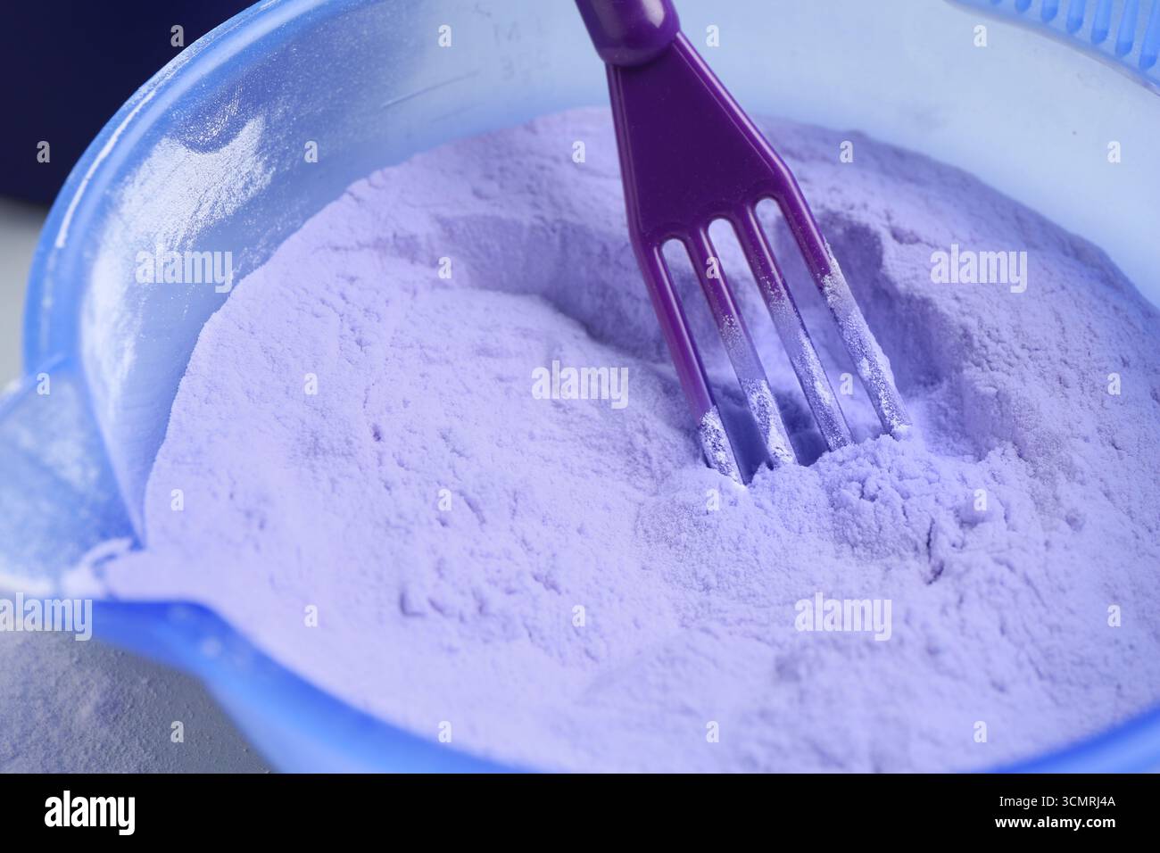 Prodotto per la cura dei capelli biondi e spatola nel recipiente, primo piano Foto Stock