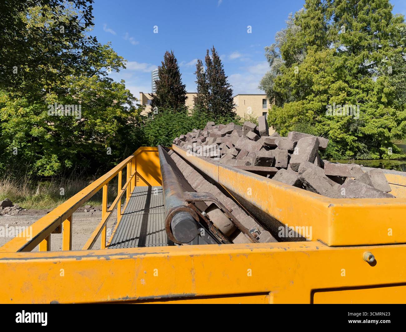 Asfaltatrice automatica al lavoro, posa efficiente di mattoni, macchina automatizzata per la costruzione di strade Foto Stock