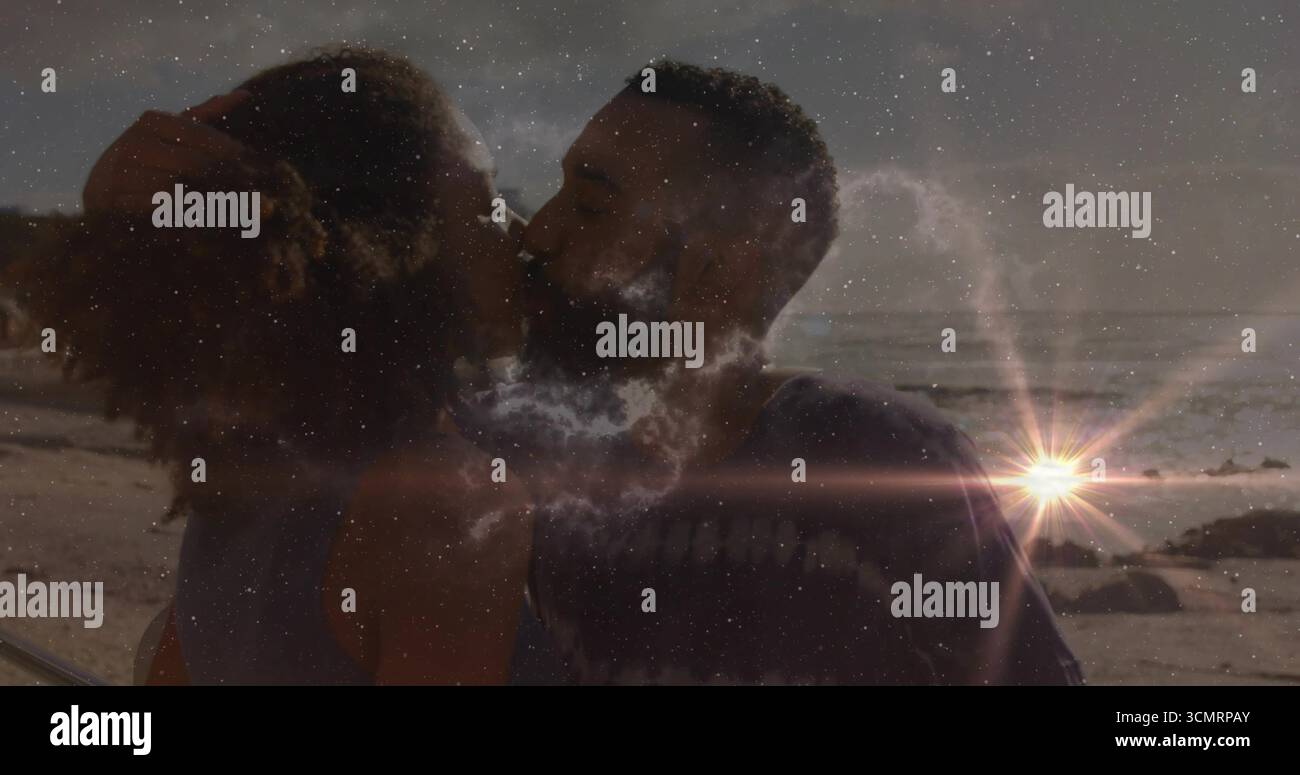 Coppia di baciatori che abbraccia la spiaggia di sabbia al tramonto, con bagliore del sole, onde dell'oceano e formazioni rocciose Foto Stock