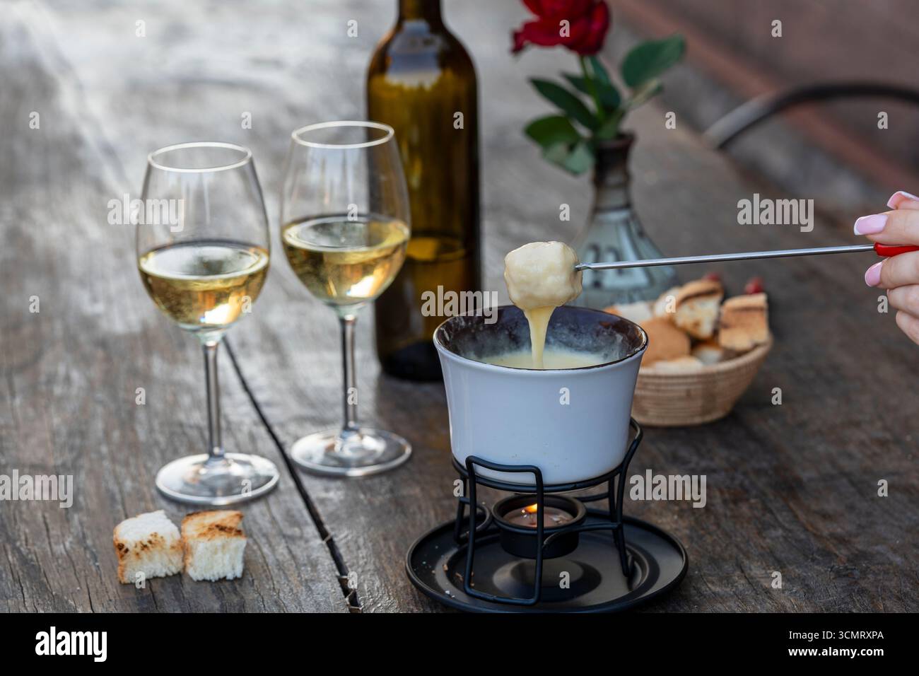 Fonduta con gustoso formaggio fuso, forchette, pane e vino su un tavolo di legno, primo piano Foto Stock