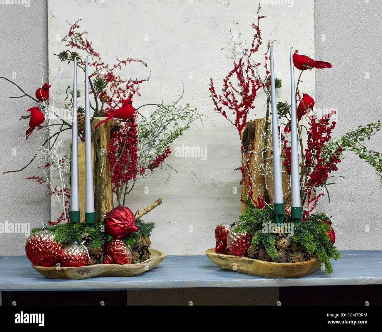 Festività natalizie con cardinali rossi, candele, rami di pino, bacche e ornamenti. Vacanza rustica che crea un ambiente caldo e commerciale Foto Stock