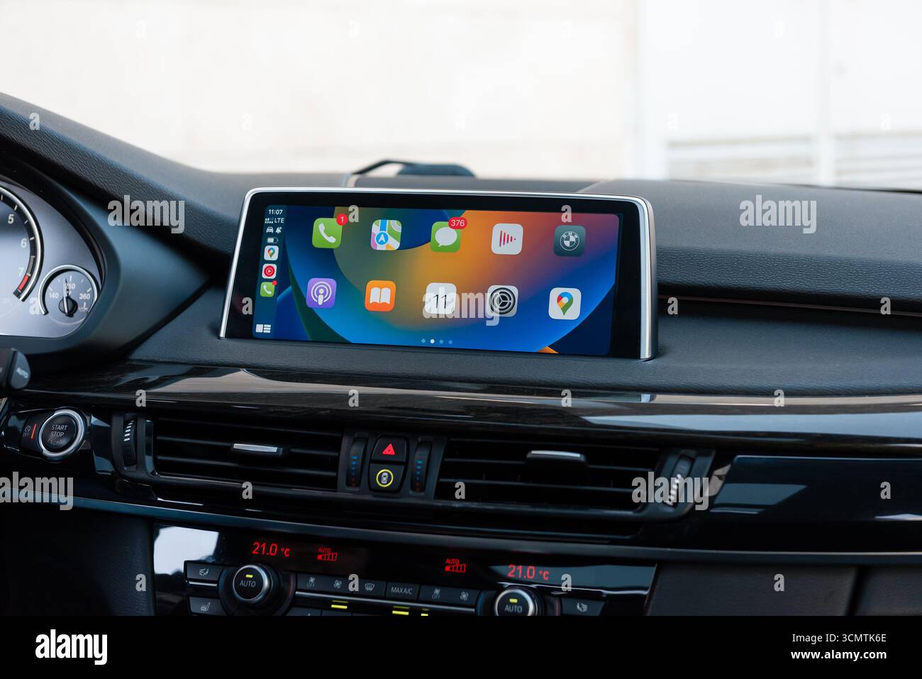Menu della schermata principale di Apple CarPlay in auto moderna. Interni dell'auto con finiture in legno lucido, primo piano del sistema di informazione e intrattenimento. Foto Stock