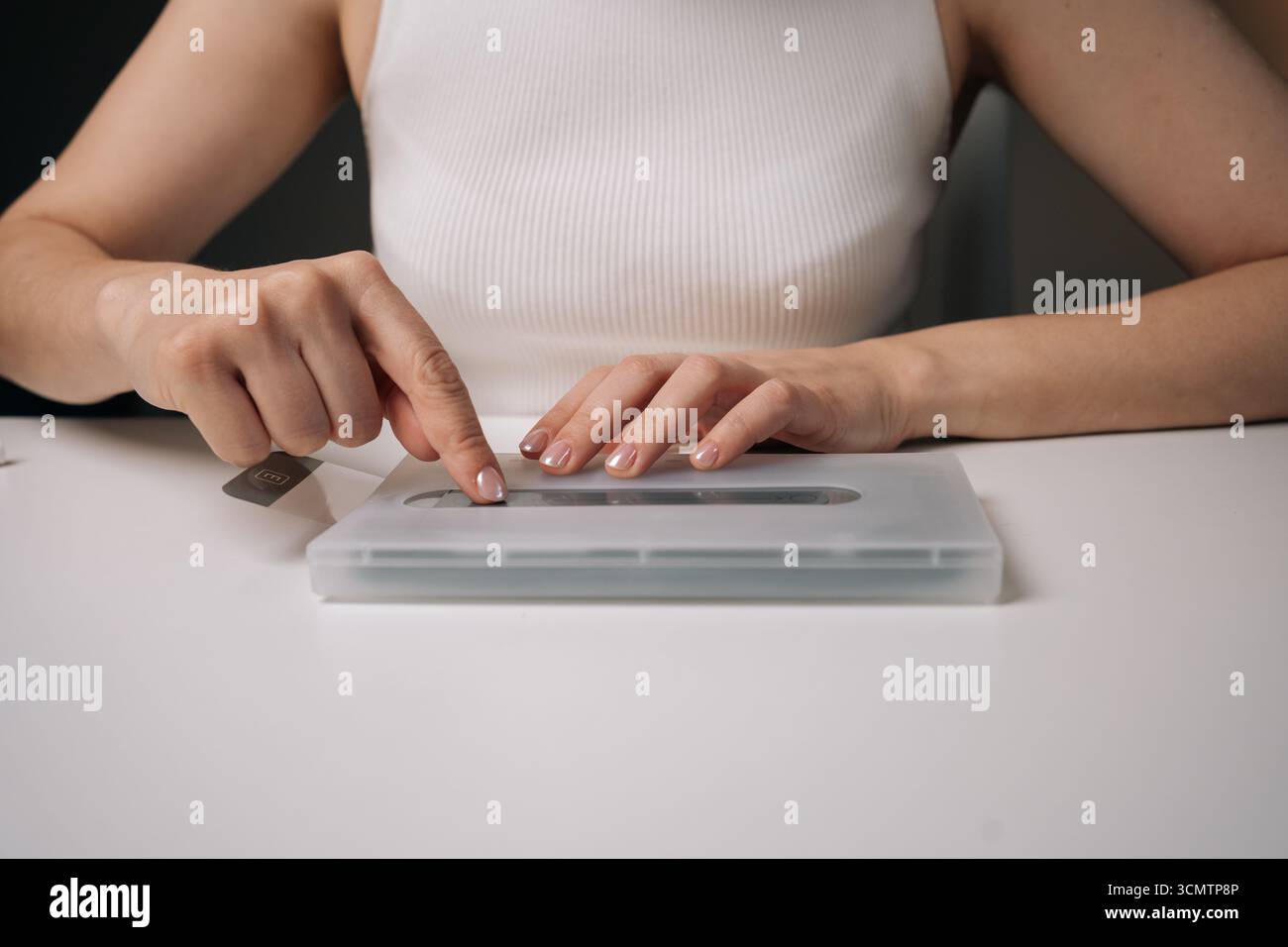 Primo piano di un tecnico donna che utilizza una macchina specializzata per applicare con precisione la pellicola protettiva in vetro sullo schermo dello smartphone, garantendo la massima copertura e. Foto Stock
