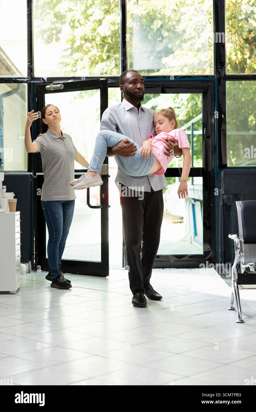 I membri della famiglia preoccupati reagiscono alla figlia inconscia in ambiente ospedaliero, affidandosi a personale sanitario professionale per cure di crisi e cure urgenti per il salvataggio della vita. Emergenza. Foto Stock