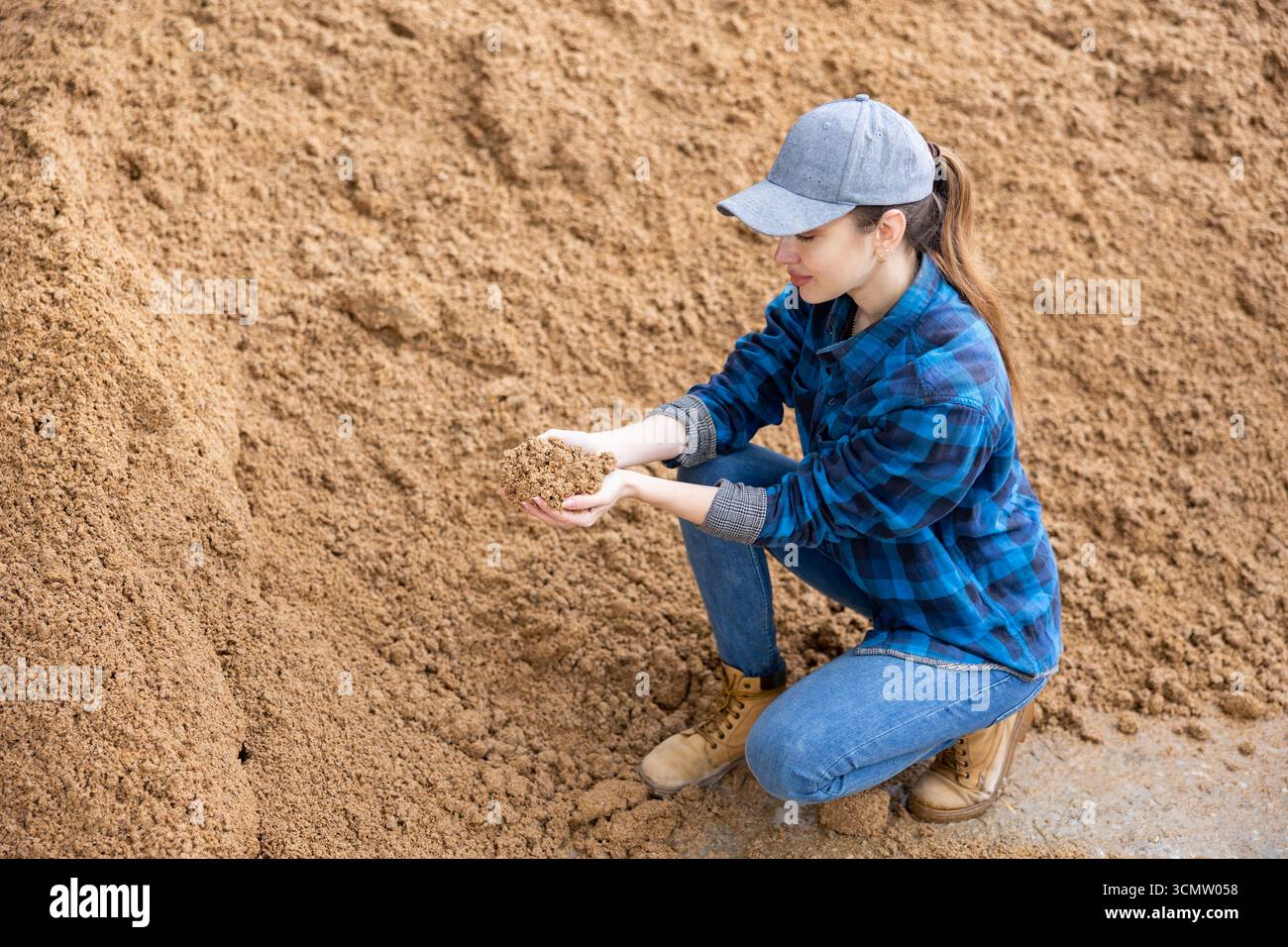 Agricoltore che controlla la qualità della bagasse di birra in un magazzino all'aperto Foto Stock