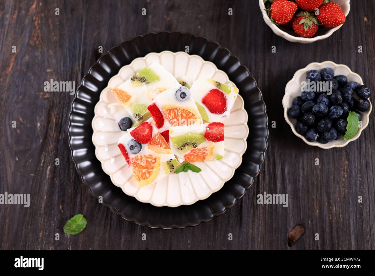Top View Bar con corteccia ghiacciata di yogurt greco fatto in casa, frutta fresca, frutti di bosco, kiwi e arancia Foto Stock