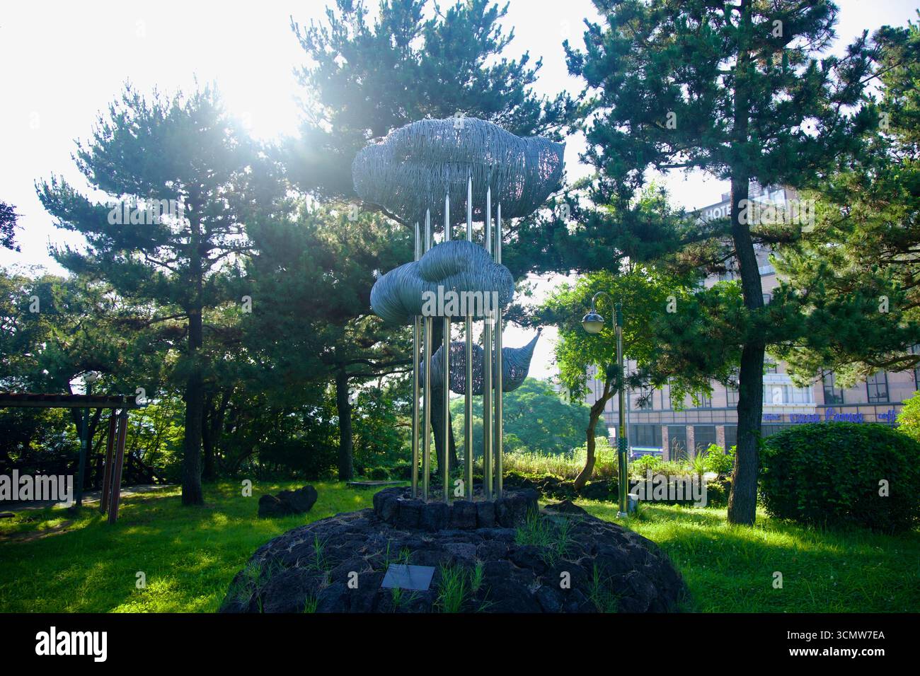 Una scultura in metallo a forma di nuvola sorge su colonne sottili tra pini e prato nel Chilsimni Park, parte delle mostre d'arte pubbliche di Seogwipo. Foto Stock