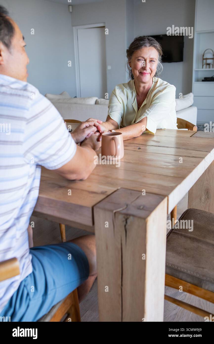 Diverse coppie che tengono le mani sul tavolo in legno nel soggiorno con tazza in ceramica Foto Stock