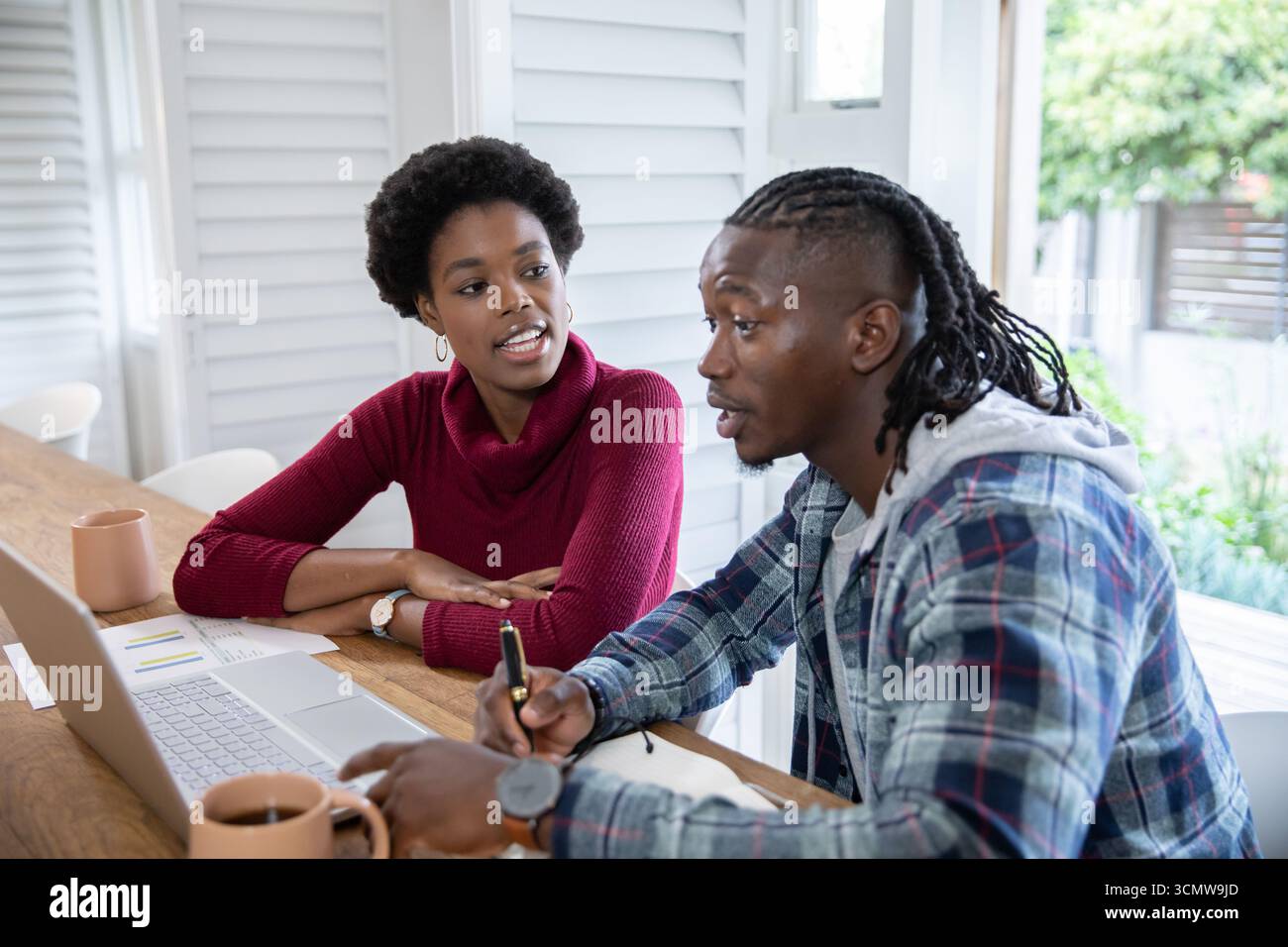 Colleghi afro-americani che collaborano con notebook, notebook con tazze a casa Foto Stock