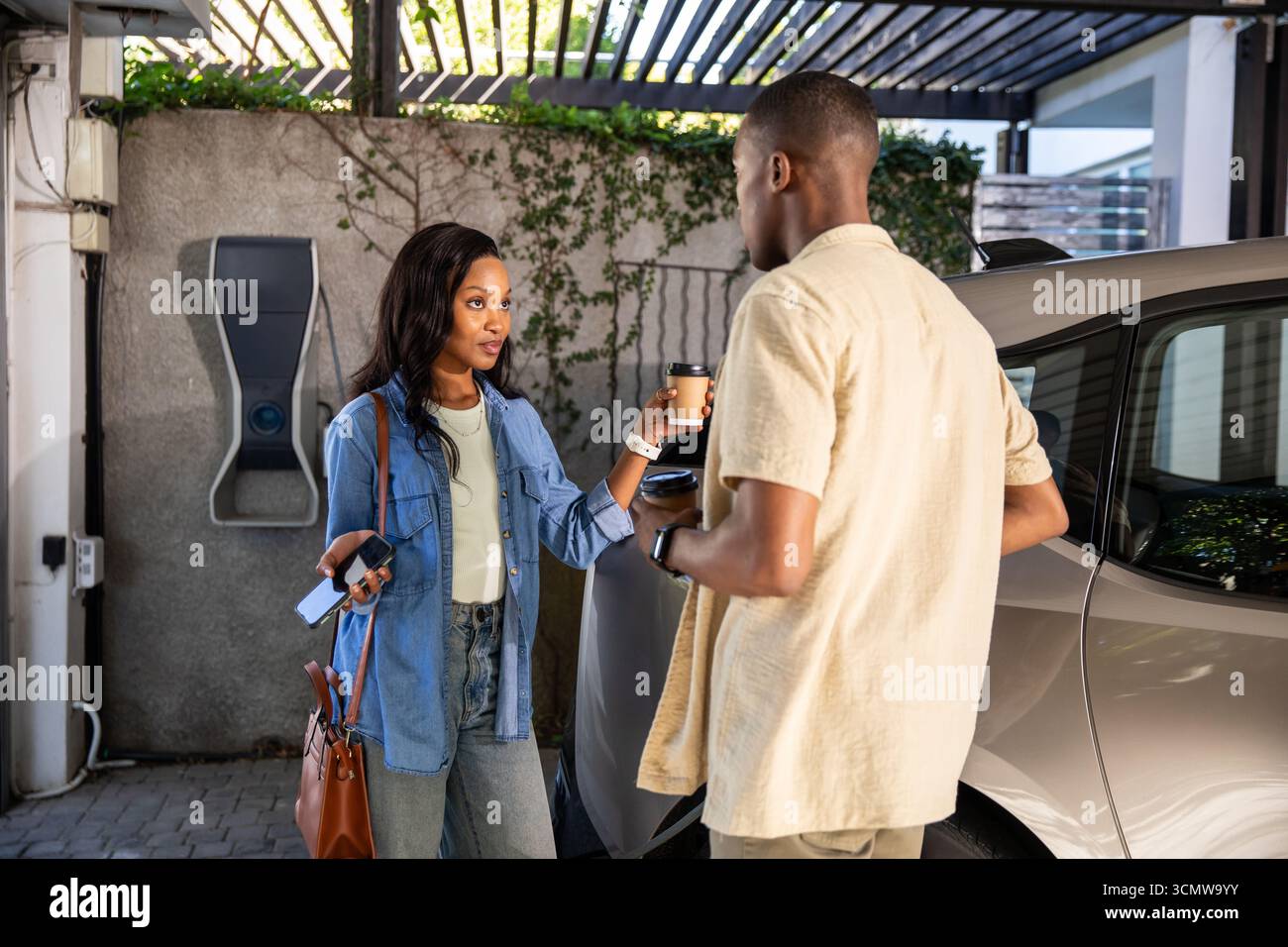 Amici afro-americani in auto con auto d'argento mentre tengono in mano tazze da caffè Foto Stock