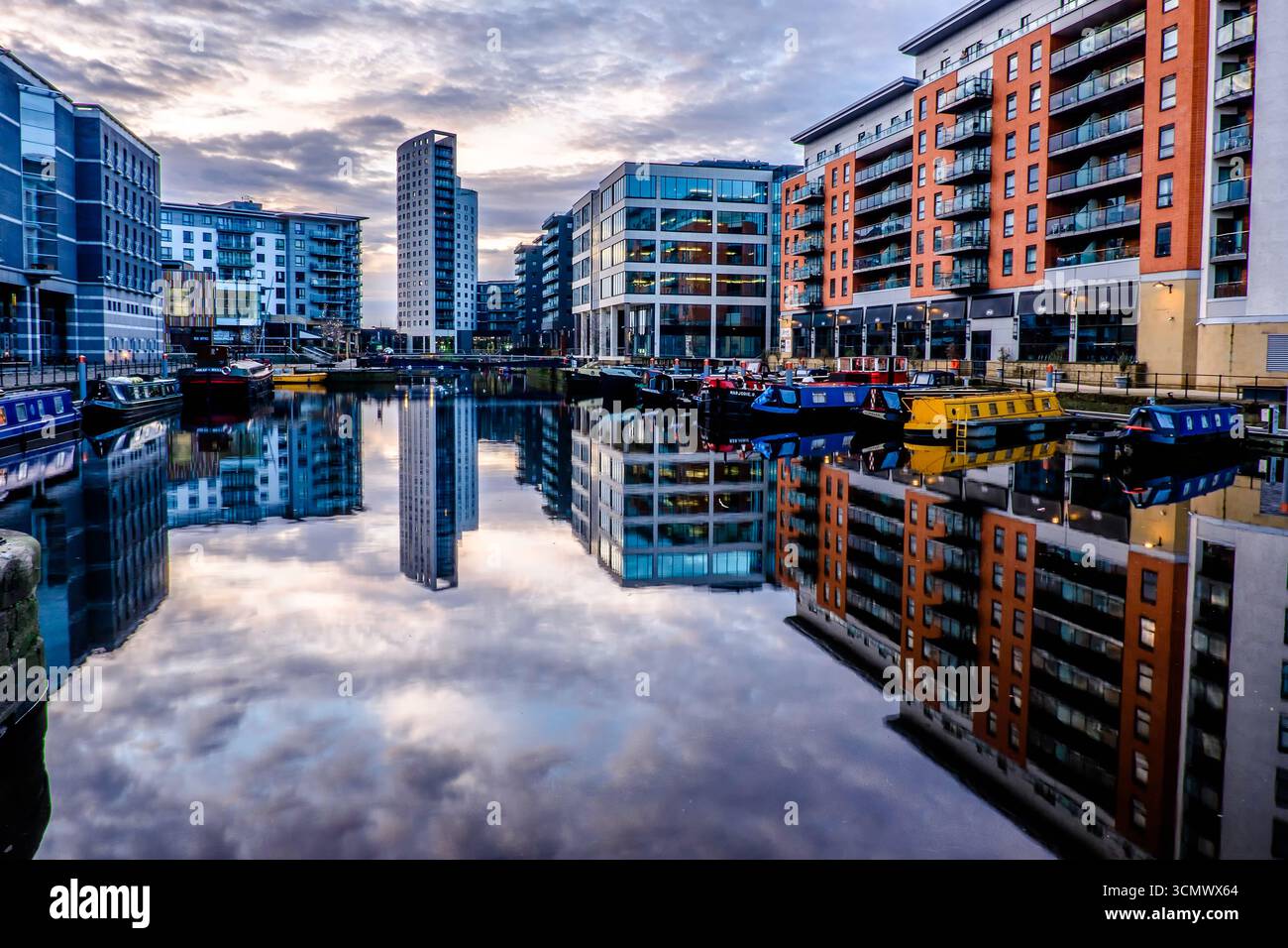 Leeds Dock con barche sul canale e moderni edifici che si riflettono nell'acqua ferma Foto Stock