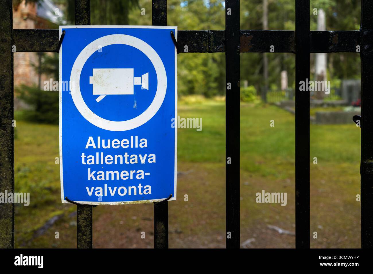 Segnale di sorveglianza di sicurezza sul cancello del cimitero con testo, che registra video sorveglianza nell'area in finlandese Foto Stock