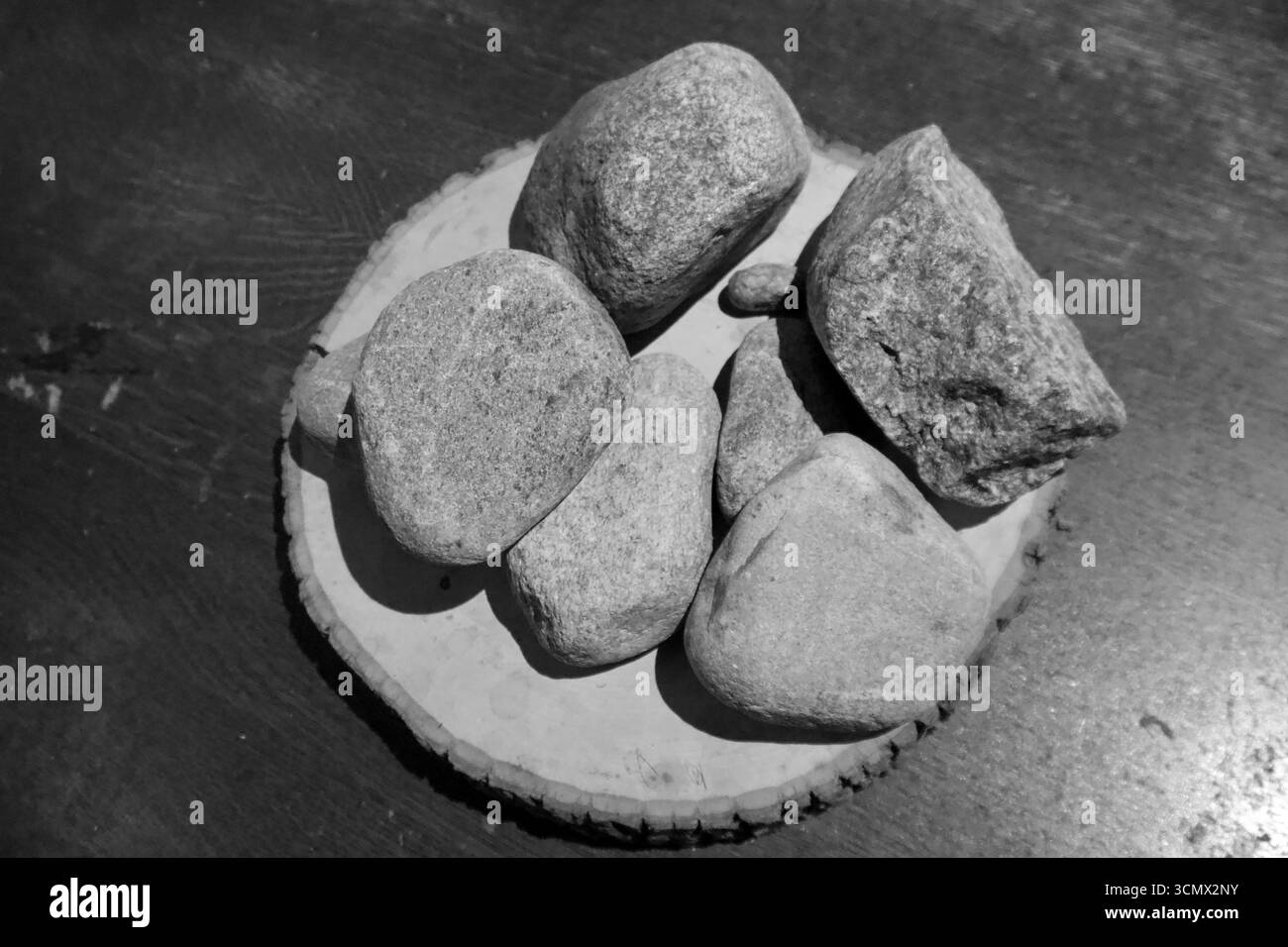 Foto in bianco e nero di pietre su base in legno in stile minimalista Foto Stock