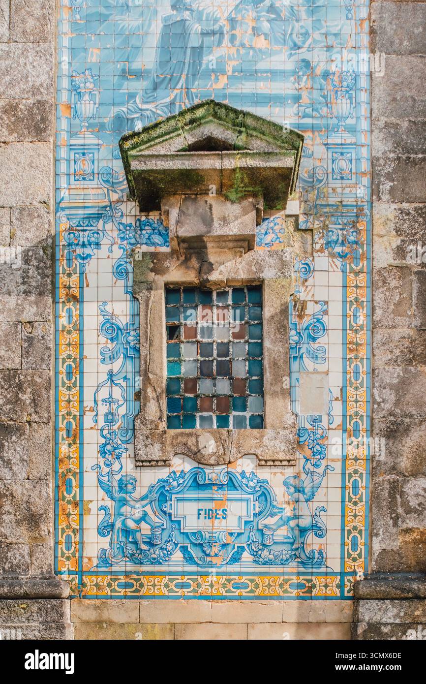 Dettaglio mattonelle di Azulejo con iscrizione latina "FIDES" e finestra incorniciata in pietra sulla chiesa di Sant'Ildefonso, Porto. Motivi ornamentali, simbolismo religioso Foto Stock