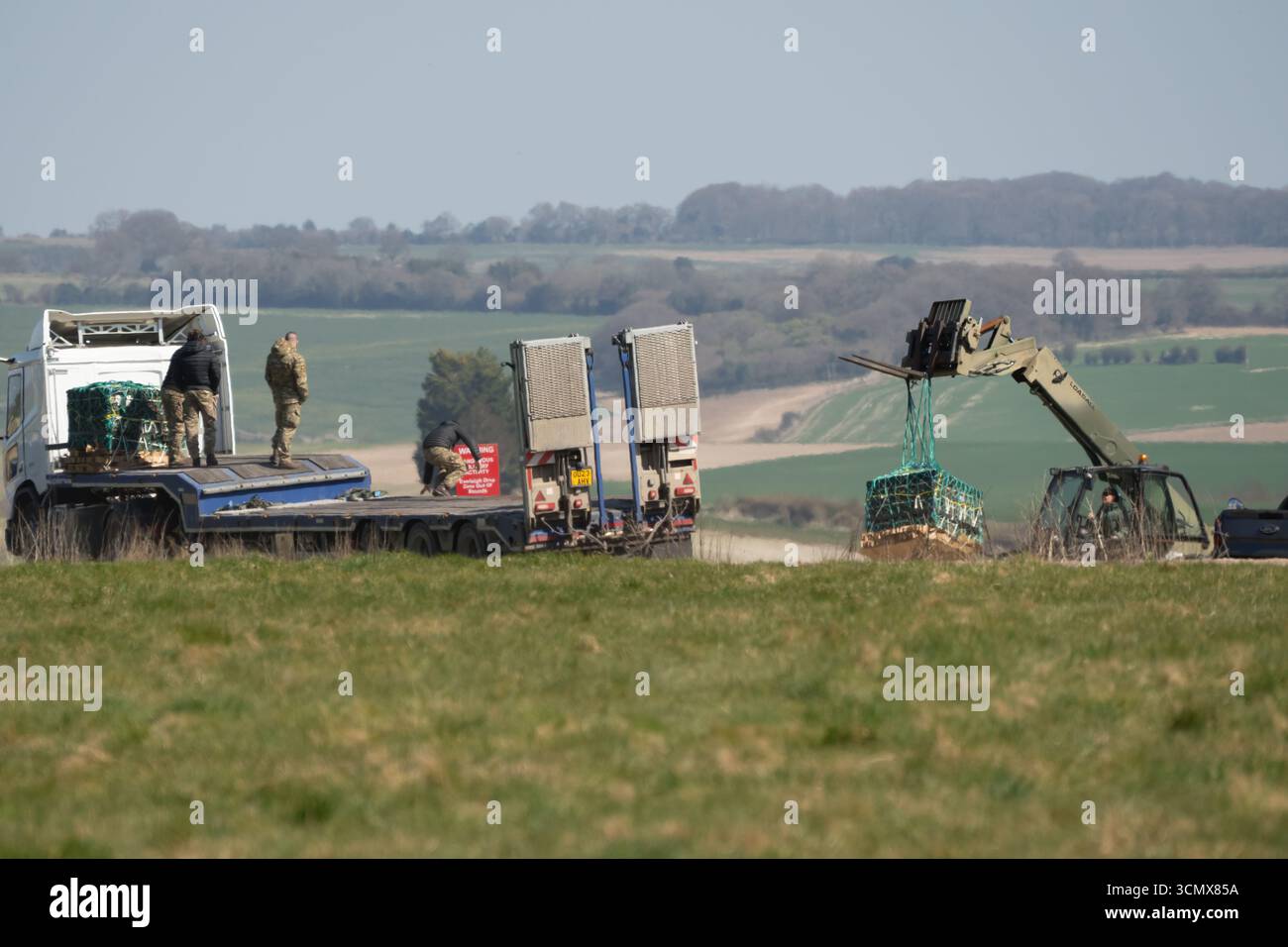 Camion logistico a pianale MAN SX 6x6 dell'esercito britannico con gru in un campo di erba verde, che recupera i pallet CDS da una caduta di paracadute Foto Stock