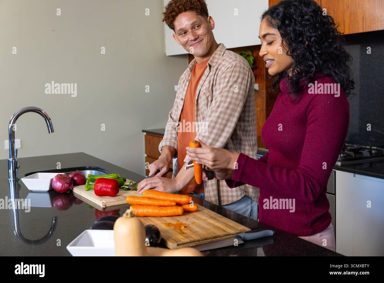 Diverse coppie di pezzi, peeling di carote fresche con coltello da cucina sull'isola di granito, copia spazio Foto Stock
