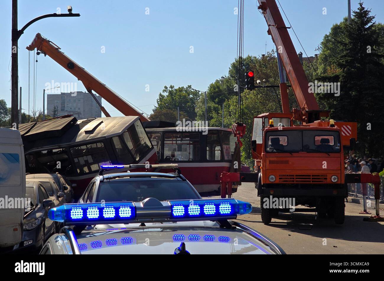 I tram deragliati si sono schiantati contro le auto per strada vengono sollevati da una gru. Foto Stock