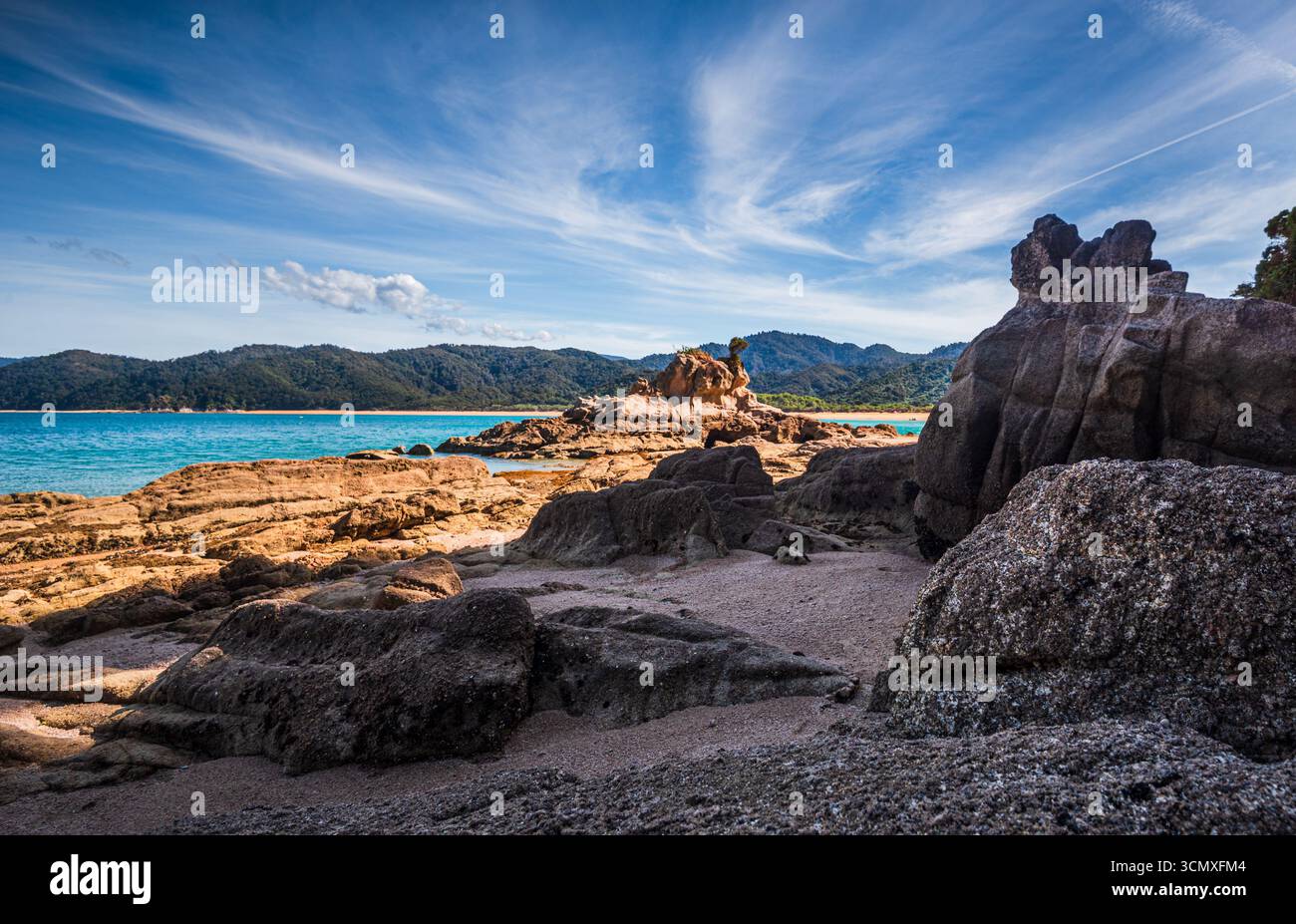 Luce d'oro sulle rocce costiere scolpite e il mare azzurro cristallino al Parco Nazionale di Abel Tasman, nuova Zelanda Foto Stock