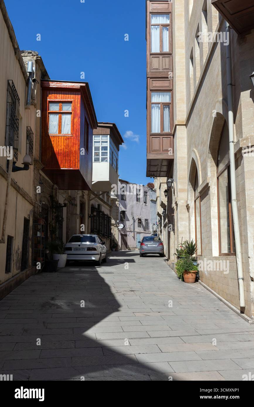 Baku, Azerbaigian - 25 marzo 2025: Una pittoresca strada cittadina con edifici classici, auto parcheggiate e un cielo limpido e soleggiato Foto Stock