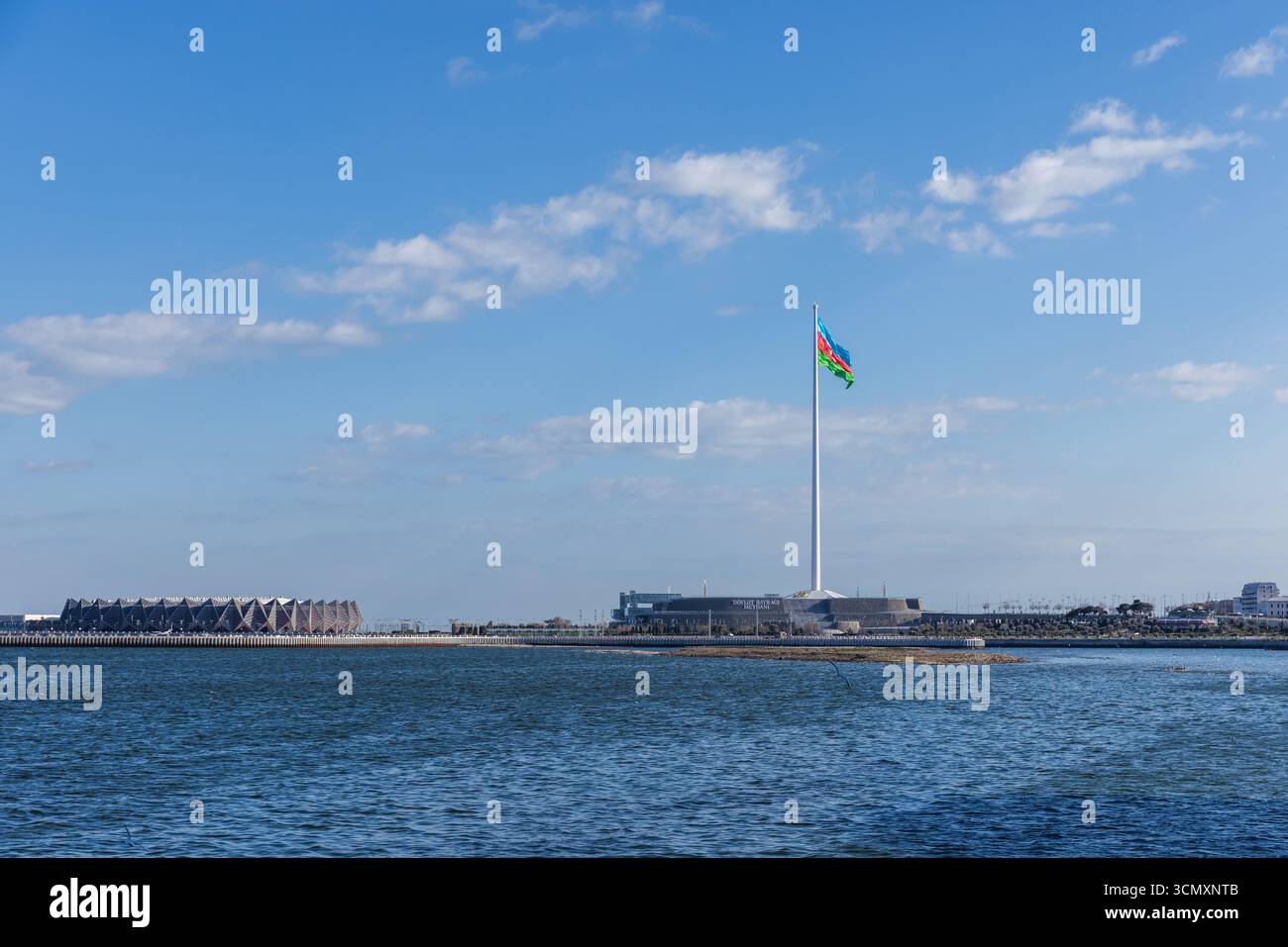 Baku, Azerbaigian - 25 marzo 2025: Vista panoramica di un punto di riferimento costiero caratterizzato da un'alta asta con una vibrante bandiera, circondato dal Parco Piazza bandiera e. Foto Stock