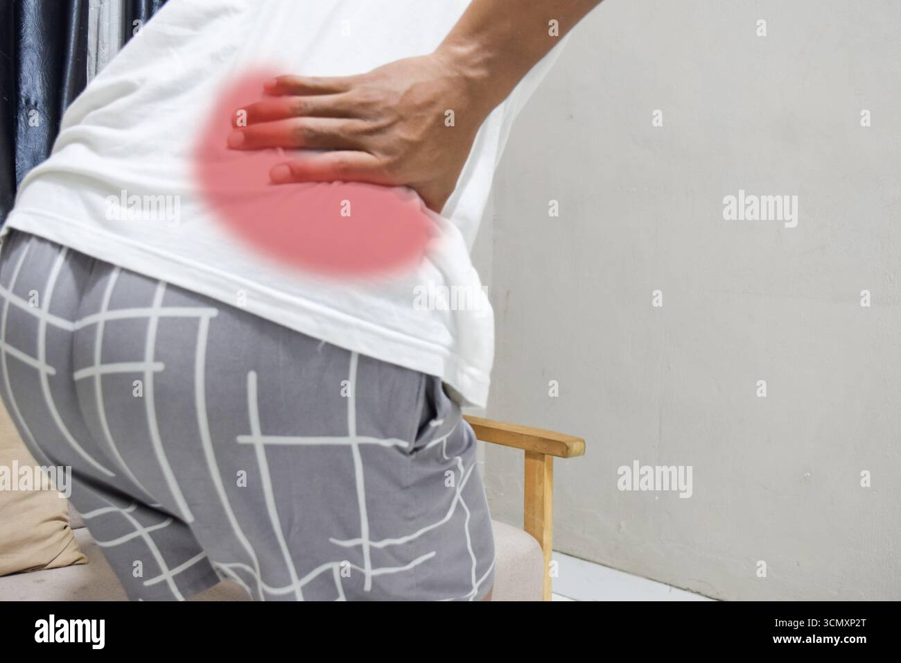 le mani del giovane uomo toccano la zona dei glutei che soffre di dolore Foto Stock