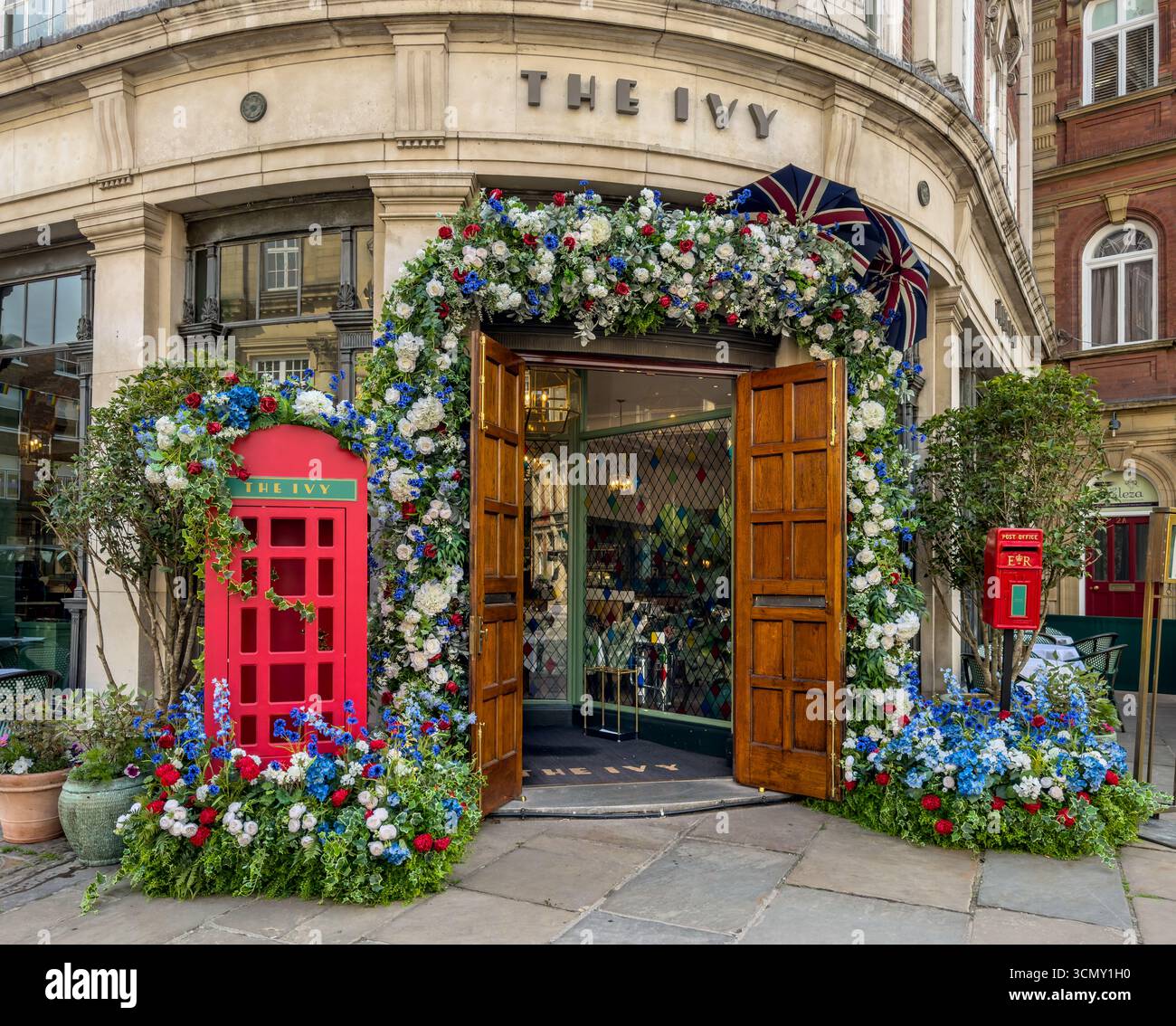 Ingresso al ristorante Ivy a York, con cabina telefonica rossa, cassetta postale e esposizione di fiori patriottici. North Yorkshire, Regno Unito Foto Stock