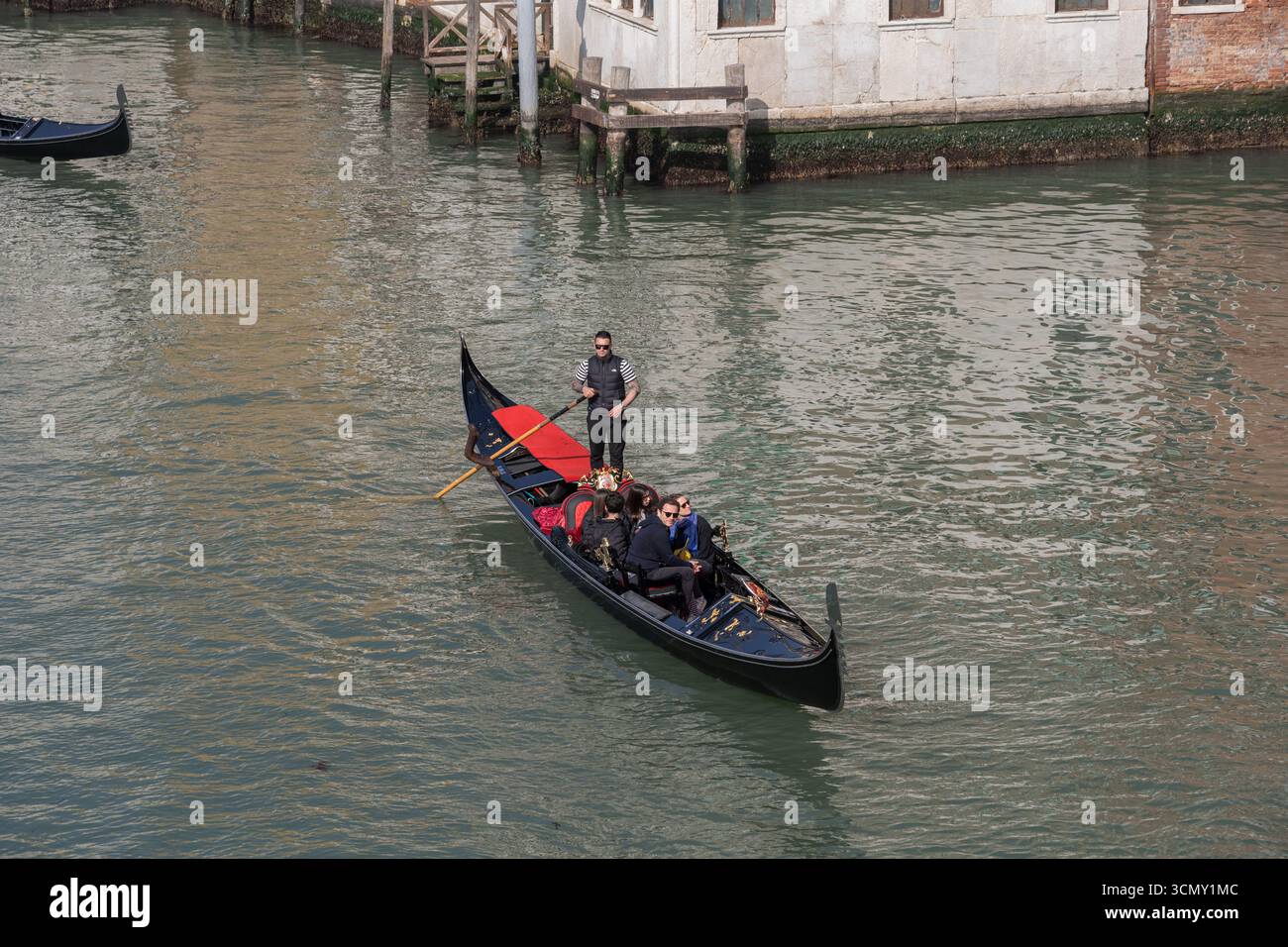 Gondola con gruppo di persone e gondoliere nel Canal grande a Venezia, Italia. Tradizionale barca veneziana con la famiglia di turisti in tour panoramico. Foto Stock