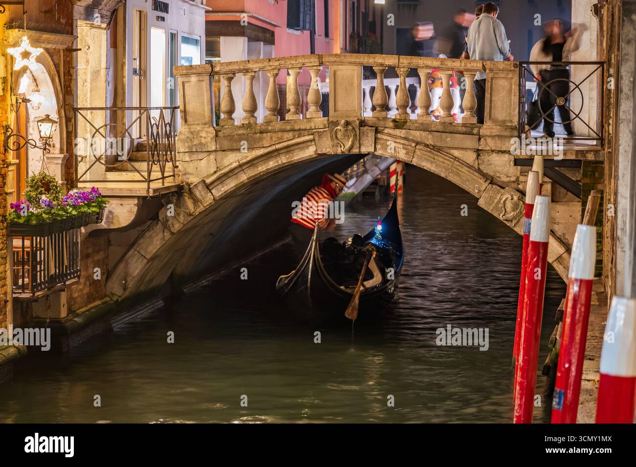 Passerella e gondola nella città di Venezia di notte in Italia. Gondoliere sotto il ponte dei Baretteri sul canale Rio dei Bareteri a San Marco Foto Stock