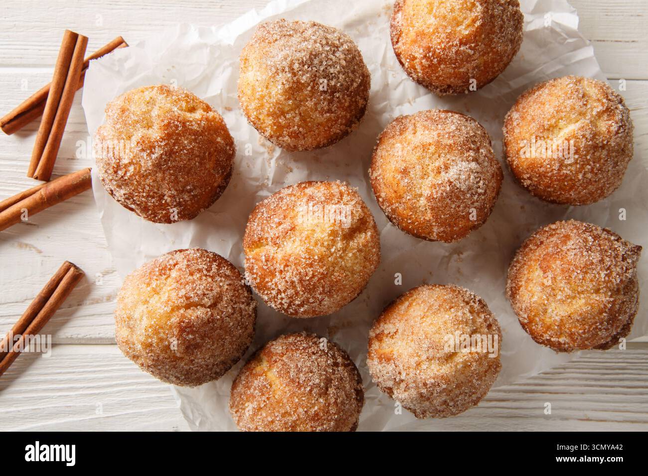 I muffin alle ciambelle sono un dolcetto super morbido e gustoso, proprio come una ciambella vecchio stile arrotolata nella cannella e zucchero da vicino sul tavolo di legno. Horizo Foto Stock