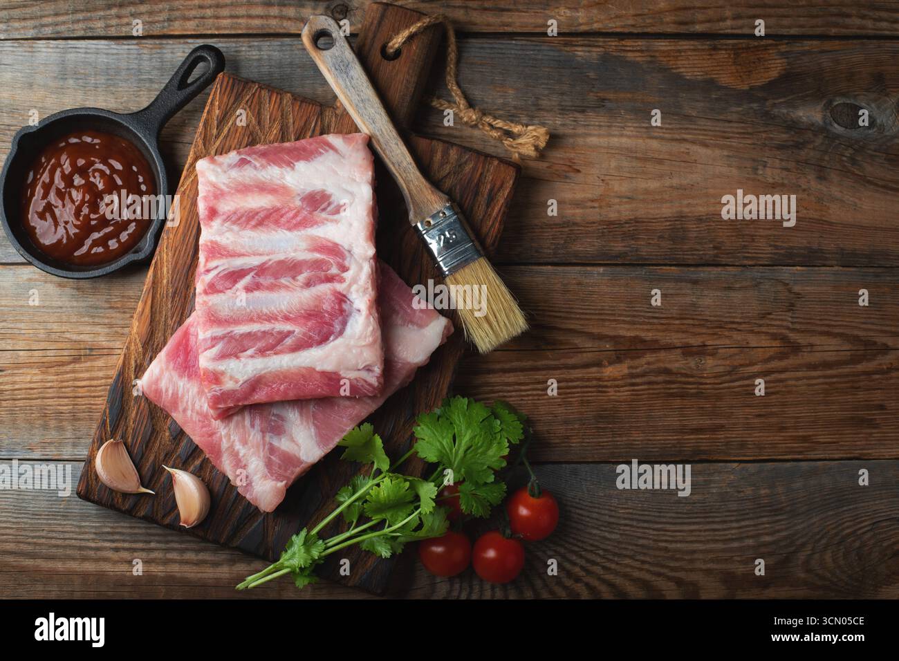 Costolette di maiale crude con spezie, sale e rosmarino su fondo di legno scuro. vista superiore con spazio di copia. Foto Stock