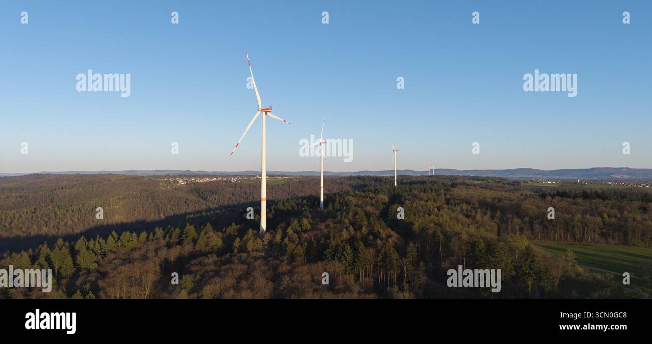 Una fila di turbine eoliche torreggia su una collina boscosa sotto un cielo limpido, vicino a Schorndorf, nella Valle del Rems, Baden-Wuerttemberg, Germania Foto Stock