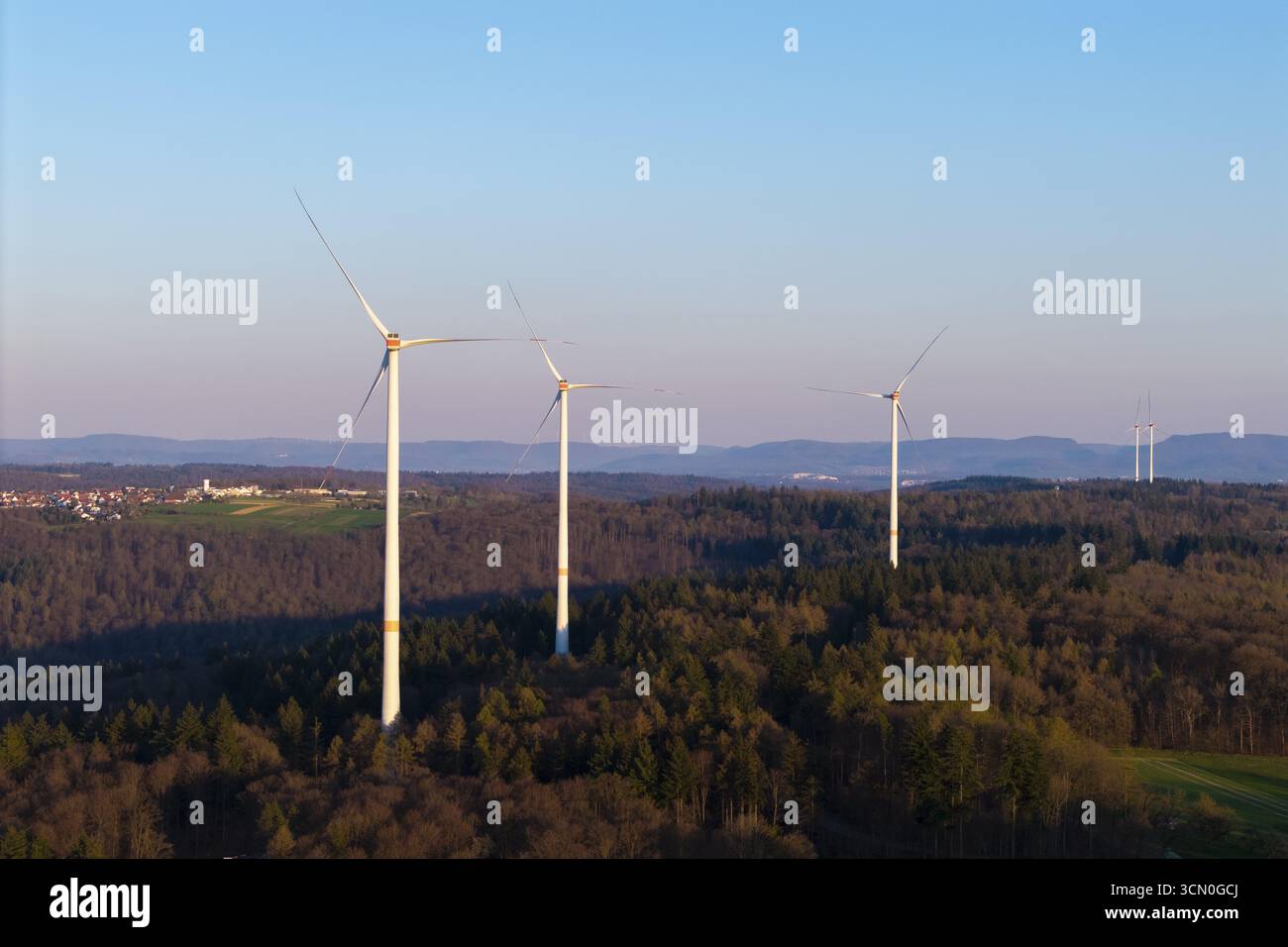 Turbine eoliche in piedi su una collina sopra una foresta, viste contro un cielo calmo, vicino a Schorndorf im Remstal, Baden-Wuerttemberg, Germania Foto Stock