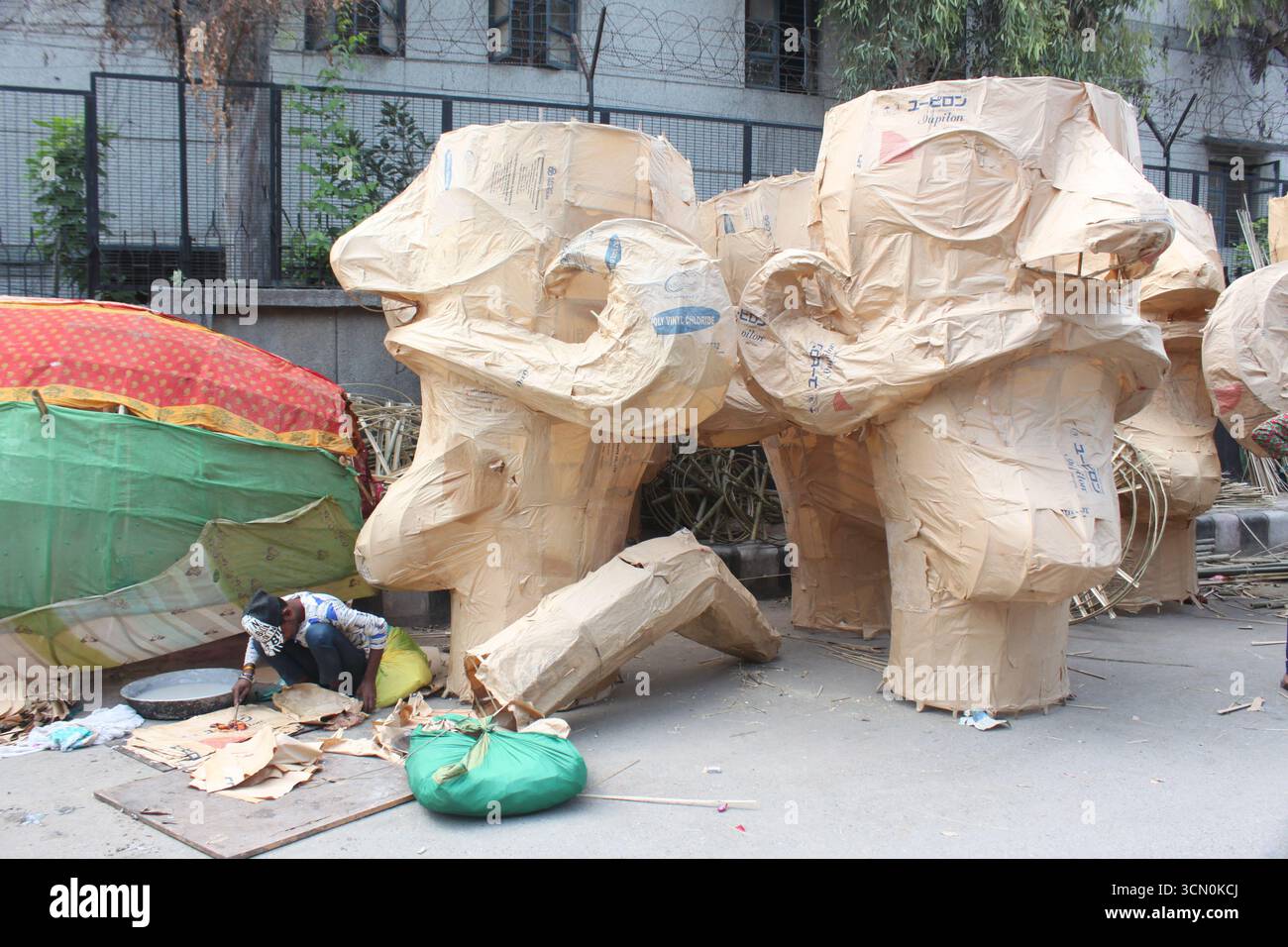 Gli artisti indiani tradizionali lavorano vicino ai volti incompleti di Ravan a Delhi, in India, in preparazione del festival Dussehra. Foto Stock