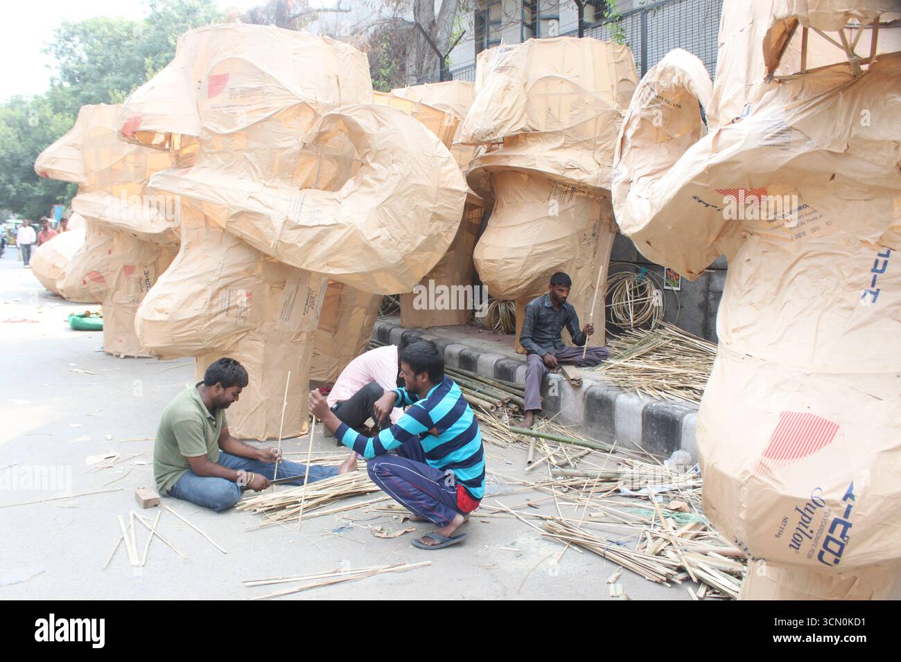 Gli artisti indiani tradizionali lavorano vicino ai volti incompleti di Ravan a Delhi, in India, in preparazione del festival Dussehra. Foto Stock