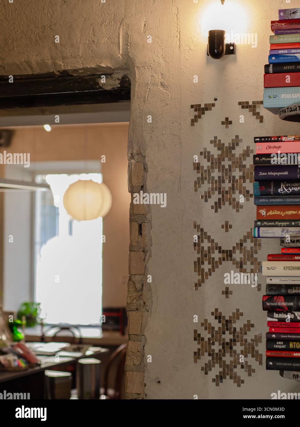 Libri impilati su scaffali a parete con lampada d'epoca in un elegante caffè interno, atmosfera rustica, Kiev, Ucraina. Foto Stock