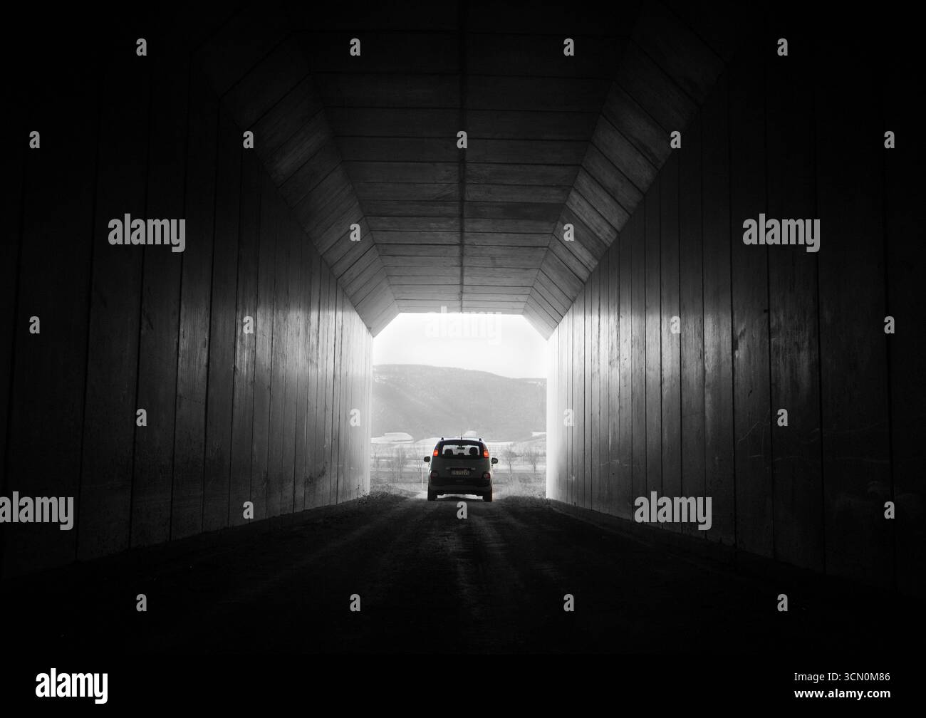 Un'auto che esce da un tunnel che simboleggia la luce alla fine del viaggio e altre metafore e sorrisi Foto Stock