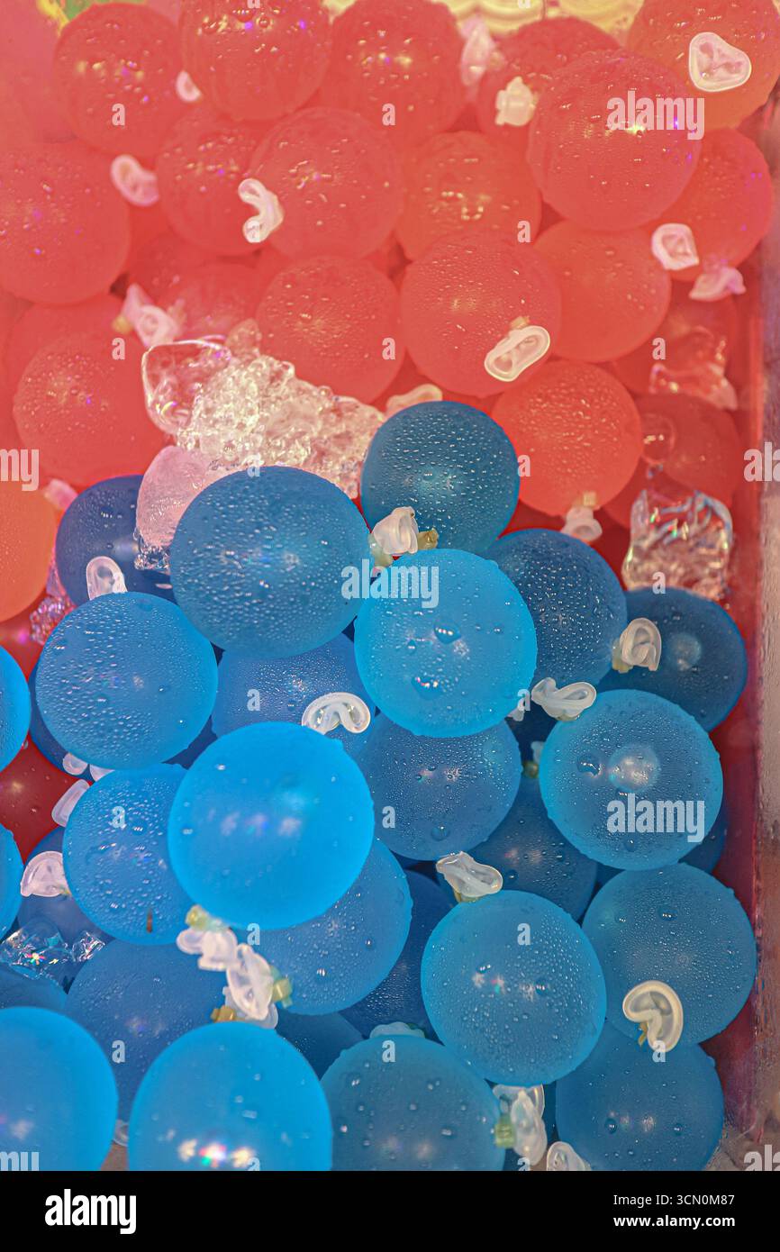 Colorata gelatina tailandese con bevande di frutta ghiacciata in sacchetti di plastica, blu e rosso, raffreddata con ghiaccio e goccioline, un fresco cibo di strada che si trova nei mercati locali. Foto Stock