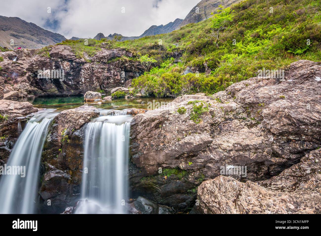Le Fairy Pools di Skye, Scozia, catturano la luce soffusa mentre le doppie tende si versano su rocce pallide, ombre annidate nel muschio e nei canali d'argento. Foto Stock