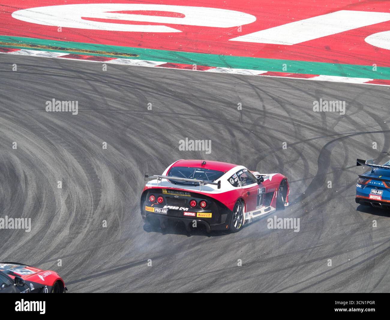 Auto da corsa scivolata in curva con fumo - Un'auto da corsa ad alte prestazioni si sposta in curva su un circuito, con il fumo degli pneumatici che sale dal suo wh posteriore Foto Stock