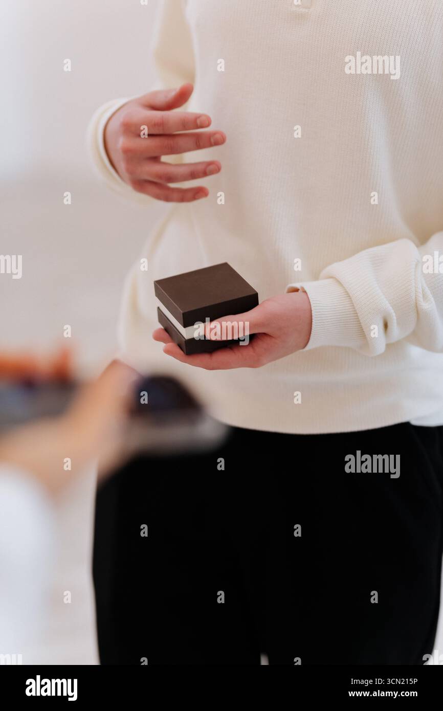 Uomo che regge un anello per una proposta, primo piano con le mani in una luce naturale soffusa Foto Stock