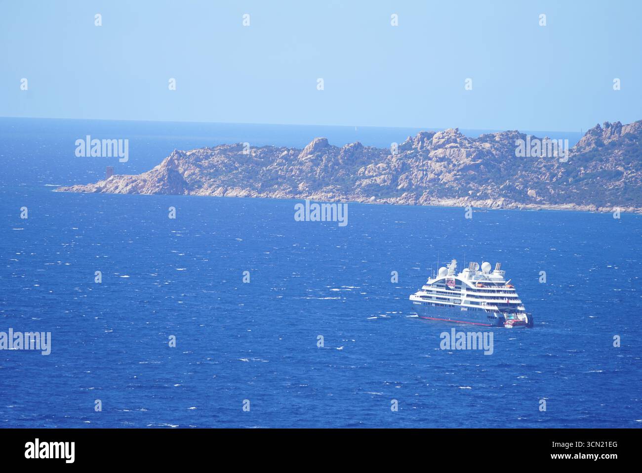 Nave da crociera che naviga nel Bright Blue Sea vicino al Rugged Island Landscape sotto Clear Sky. Bonifacio, Corsica, Francia Foto Stock