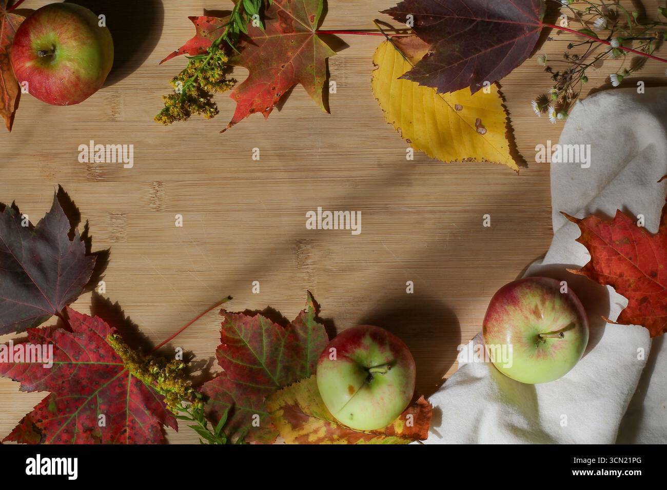 Tagliere in legno con mele e foglie autunnali, piatto con spazio per copie Foto Stock