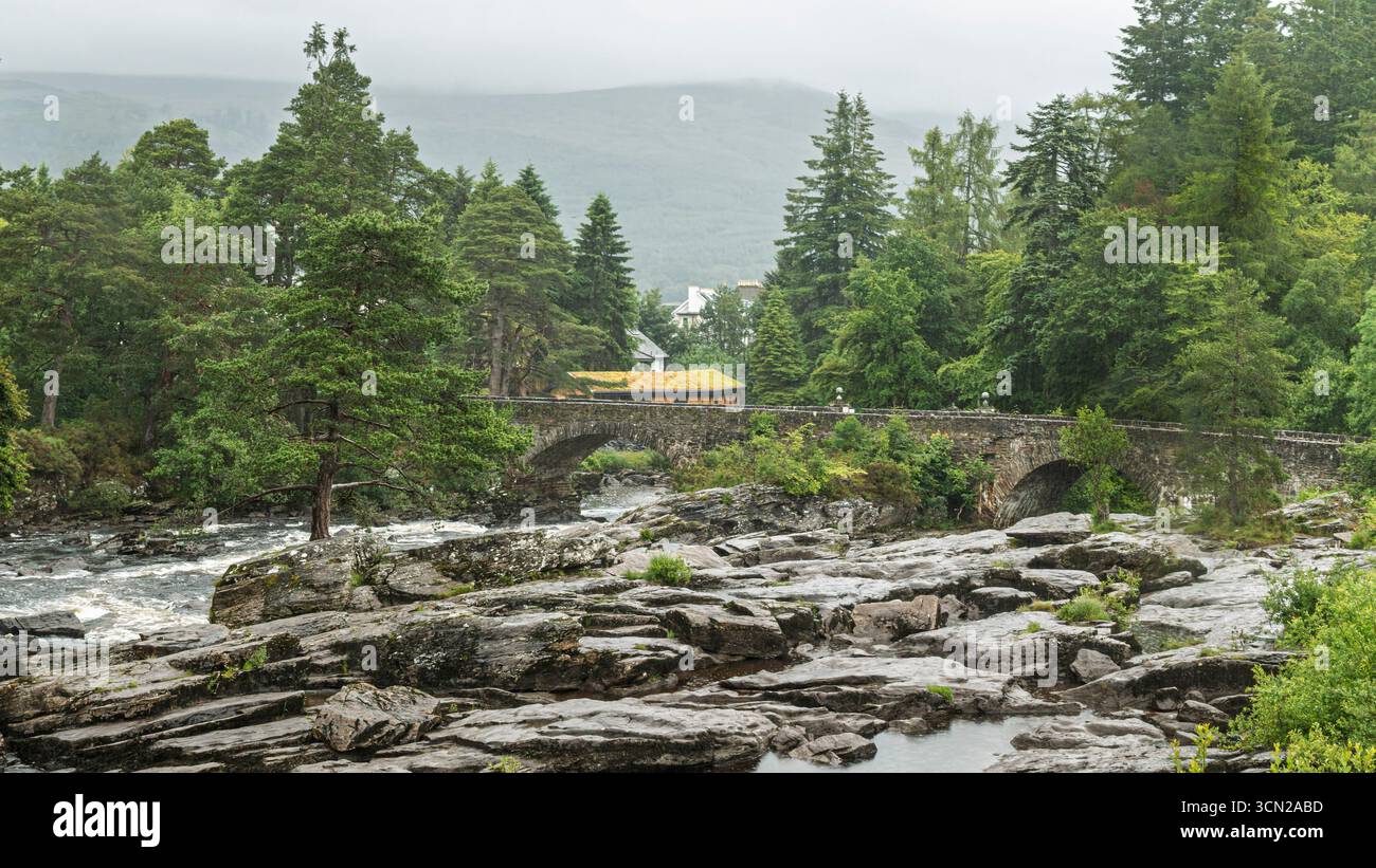 Regno Unito - Killin - Falls of Dochart - ponte di pietra e fiume schiumoso che corre sulle rocce scure delle Highland Foto Stock