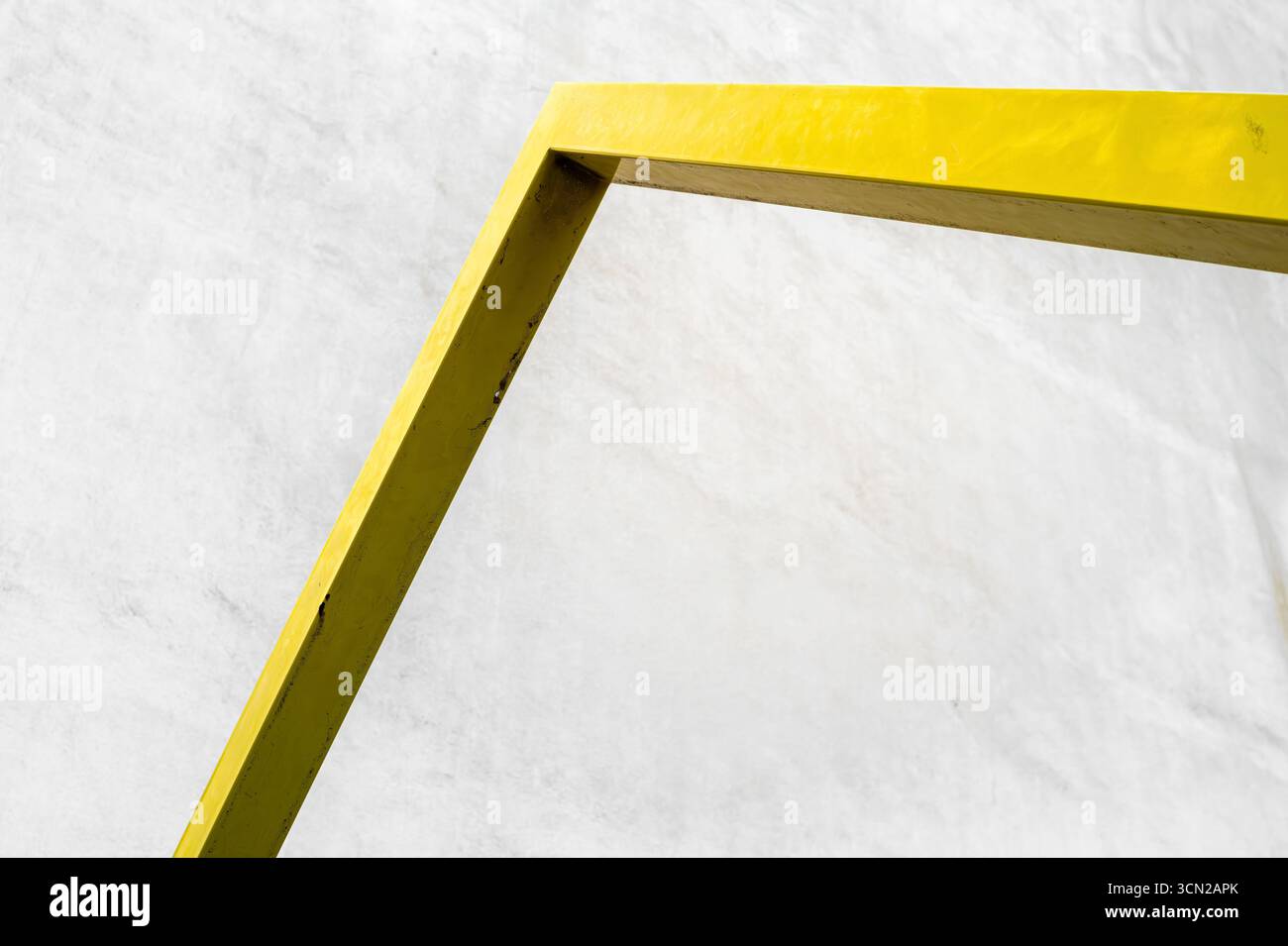 Immagine minimalista di una cornice in metallo giallo contro una parete testurizzata bianca. Foto Stock