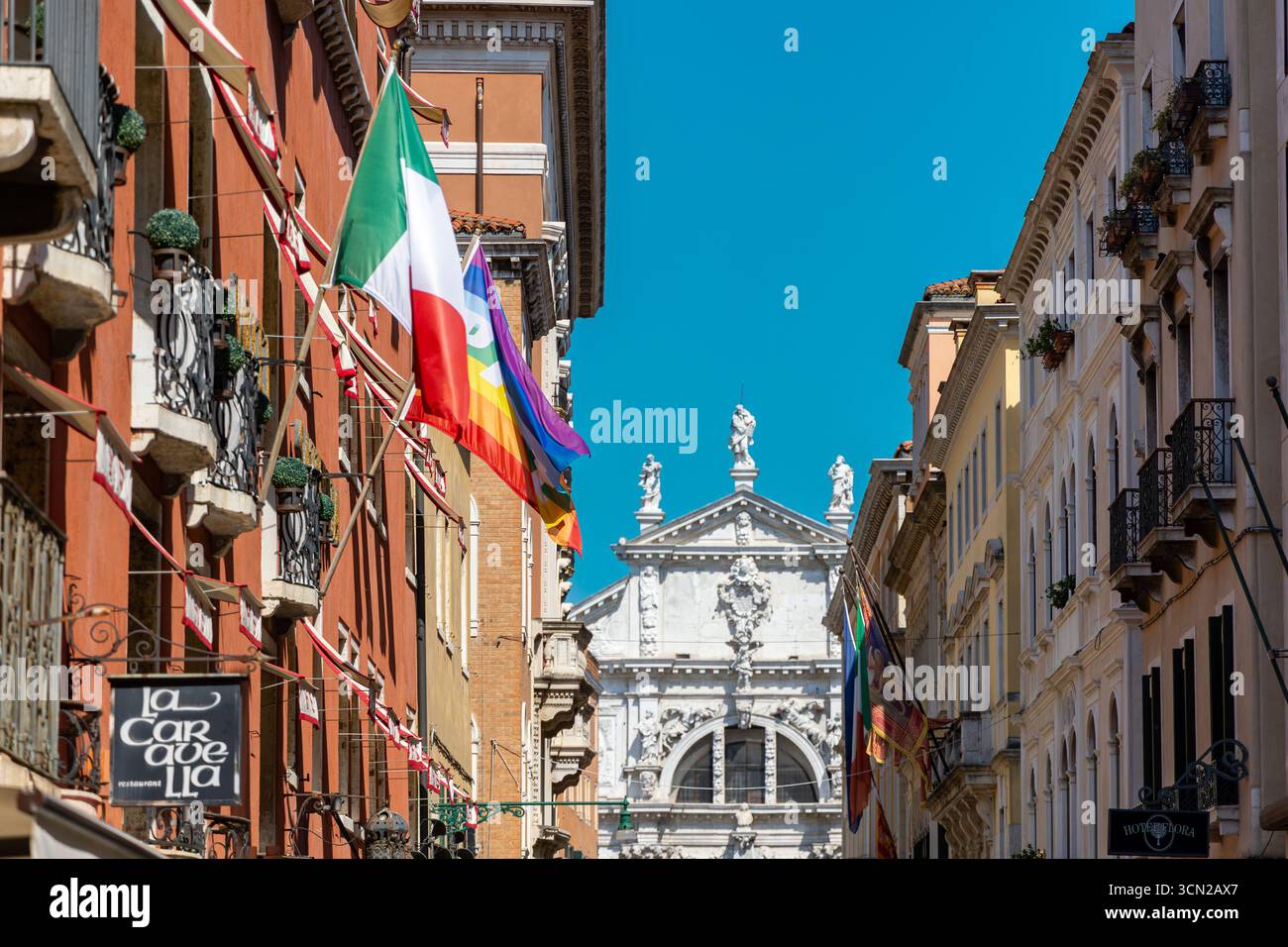 Venezia, Italia, 11 agosto 2025: Bandiere colorate e chiesa ornata a Venezia Foto Stock